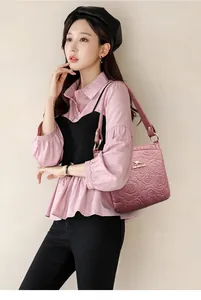 Detail of 3D rose embossed leather bucket bag in dusty rose with golden logo