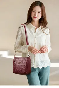 Detail of burgundy leather bucket bag with 3D embossed rose pattern and gold logo