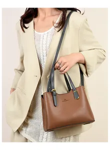 Dettaglio della borsa in pelle marrone con finiture dorate su un blazer beige