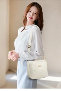 Detail of white embossed leather bucket bag with rose pattern and gold hardware accents
