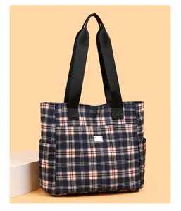 Détail du sac cabas à carreaux avec poche zippée frontale et plaque en métal chic