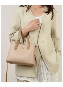 Dettaglio della borsa beige in pelle con trama a litchi e finiture in metallo dorato