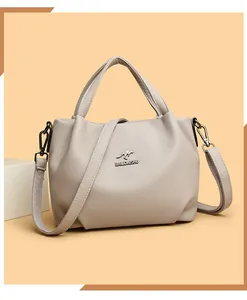 Detail of genuine leather lychee texture and kangaroo metal logo on a grey handbag