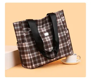 Détail du sac cabas à carreaux marron avec poches latérales et plaque en métal