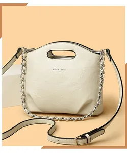 Detalle de bolso saco plisado crema con cadena plateada y cierre de cremallera