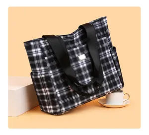Détail d'un sac cabas à carreaux noirs et blancs avec bandoulière et poche latérale