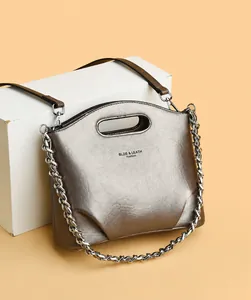 Detalle de bolso saco de cuero metalizado bronce con cadena de plata y asa calada