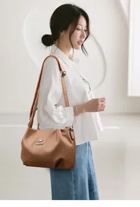 Close-up of caramel brown leather handbag with litchi texture and silver kangaroo logo
