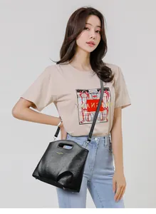 Detalle del bolso tipo cubo de cuero arrugado negro con asa superior y correa