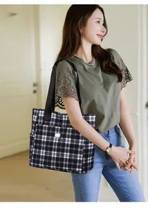 Détail d'un grand sac cabas à carreaux noir et blanc avec poches latérales et logo