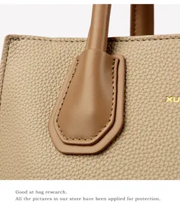 Detailed macro view of brown pebbled leather texture and gold embossed XU logo on tote bag