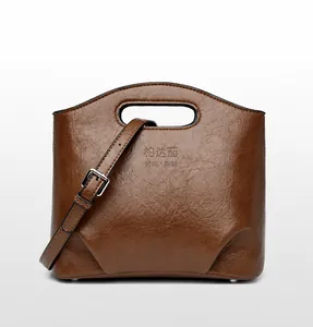 Detalle de bolso bucket de cuero marrón con textura de lichi y asa calada elegante