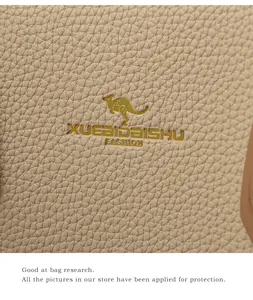 Detail of beige lychee grain leather with gold kangaroo logo on elegant tote bag