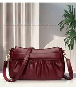 Detail of burgundy ruched leather crossbody bag with lychee grain and gold hardware