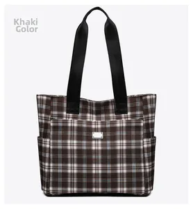 Détail frontal du sac cabas à carreaux kaki avec motif écossais et plaque en métal