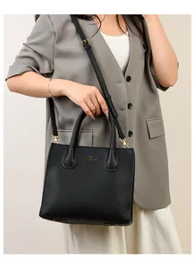 Detail of black pebbled leather tote bag with adjustable strap and gold metal hardware