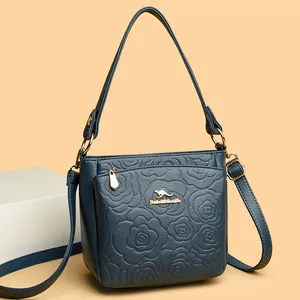 Dark blue leather bucket bag featuring floral embossing and gold hardware detail