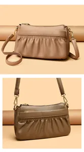 Detail of lychee textured leather and pleated design on a tan crossbody bag with gold hardware
