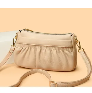 Detail of beige pleated leather crossbody bag with lychee texture and gold metal hardware