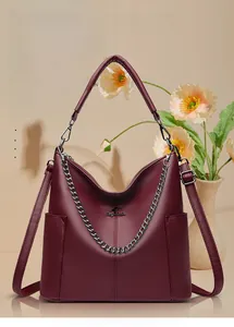 Detail of burgundy leather bucket bag with litchi texture and golden chain strap