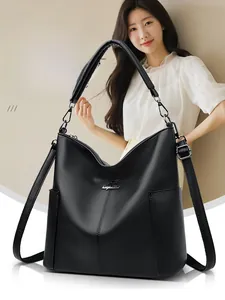 Detail of black pebbled leather hobo bag showing metallic logo and side pocket feature