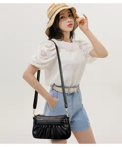 Detail of black pleated leather shoulder bag worn by model in a summer casual outfit