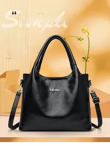 Détail de la texture cuir noir grainé et du logo métallique argenté sur le sac à main