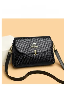 Detail of woven texture black leather bag with gold kangaroo logo and metallic buckle