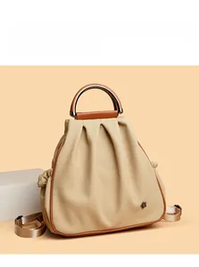 Detail of beige canvas and brown leather bag with bee logo and metal round handle