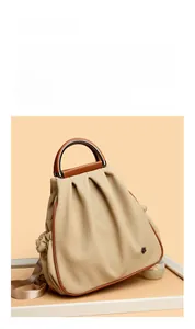 Detail of beige canvas shoulder bag with brown leather trim and round metal handle