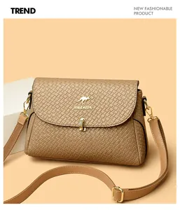 Close-up of khaki woven leather flap bag with gold kangaroo clasp and strap detail