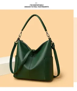 Detail of dark green pebble leather tote bag with metallic logo and sturdy handles