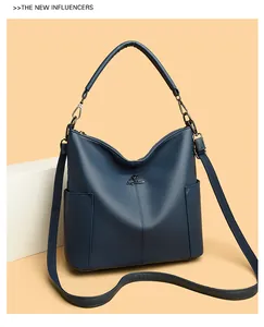 Detail of dark blue lychee leather bag featuring a gold kangaroo metal emblem and texture