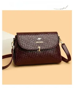 Macro view of woven leather texture and golden metal lock on burgundy crossbody bag