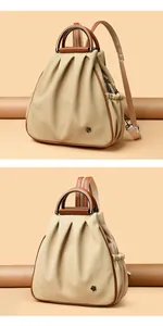 Detail of beige canvas backpack with brown leather trim and elegant metal flower logo
