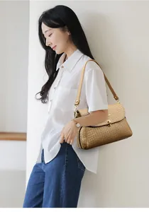 Detailed close-up of woven leather texture and golden clasp on a brown crossbody handbag