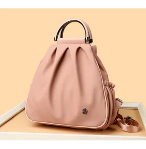 Detailed view of dust pink pleated bag featuring elegant metal camellia floral ornament