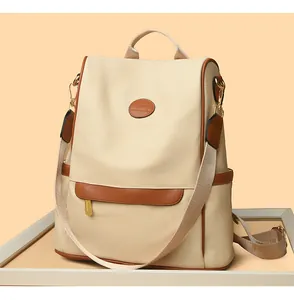 Detail of beige Oxford cloth backpack featuring brown PU leather trim and kangaroo patch