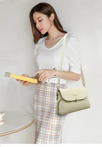 Detail of elegant cream textured leather crossbody bag with golden kangaroo logo