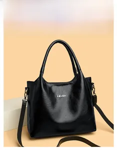 Détail du sac cabas en cuir noir avec logo en métal argenté et large bandoulière amovible