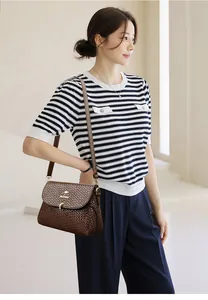 Brown woven leather shoulder bag with a metal kangaroo logo shown on a fashion model