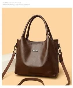 Détail du logo en métal argenté et de la texture cuir sur un sac cabas marron vintage