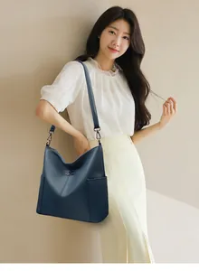 Close-up of navy blue leather tote bag showing grainy texture and golden kangaroo logo