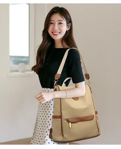 British style beige canvas backpack with brown leather details worn by a model in a room