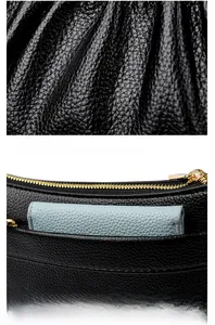 Detail view of black lychee grain leather crossbody bag showing rear pocket and gold zipper