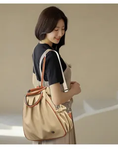 Detail of beige canvas backpack with brown leather trim and metal ring handle design