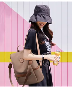 Detail of khaki water-resistant backpack showing leather kangaroo logo and side pockets