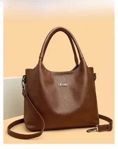Gros plan du logo Yifutin argenté sur la texture cuir marron de ce sac à main porté