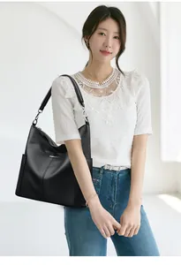 Close-up of litchi grain leather texture and silver logo on black bucket bag