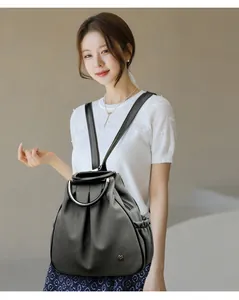 Detail of grey backpack with woven texture and circular metal handle on a model